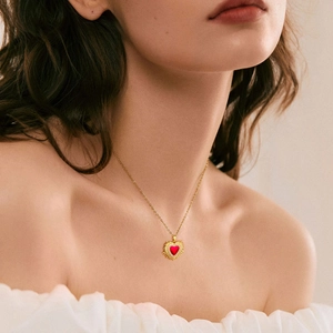 Dettaglio di una collana placcata oro con ciondolo a cuore rosso e diamanti su modella