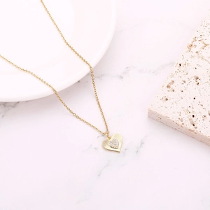 Detailed macro view of heart-shaped gold necklace with radial engravings and zircon inlay