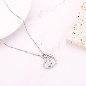 Macro shot of silver heart pendant with MOM design and pavé cubic zirconia details
