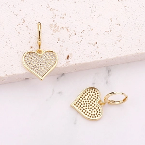 Elegant heart pendant earrings with gold plating and paved zircons on marble background
