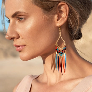 Detail of bohemian drop earrings with colorful beads and feathers on golden frames