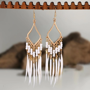 Detail view of Bohemian long earrings with white feathers and beads on wood stand