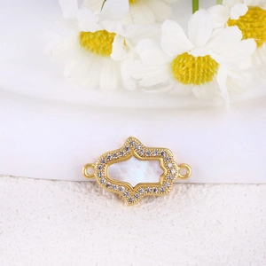 Vista macro del colgante Hamsa dorado con nácar y circonitas para creación de joyas