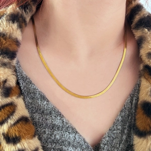 Nahaufnahme der goldenen Schlangenkette an Model mit modischem Leopardenmuster-Hintergrund