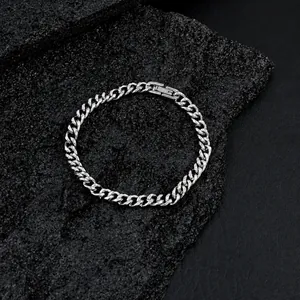 Polished silver Cuban link bracelet on dark rock, featuring a secure fold-over clasp