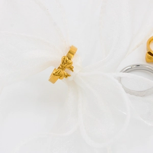 Macro di un anello a fiocco d'oro lucido su nastro di organza bianca per uno stile chic