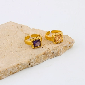 Vintage gold adjustable rings with square purple and champagne zircons on stone background