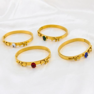 Detail view of four gold-plated bangle bracelets featuring rose motifs and colorful gemstones