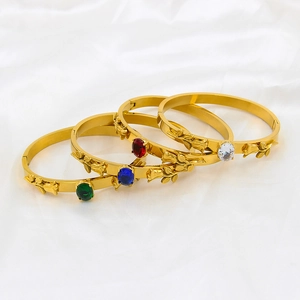 Detail of four gold bangles with colorful gemstones and vintage rose relief carvings