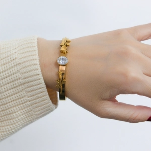 Detail of rose gold flower bracelet with sparkling zircon on a white knit sweater