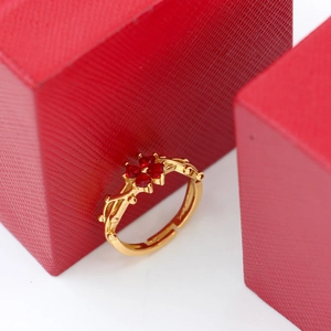 Detail of gold clover ring featuring four red heart-shaped stones and beaded band