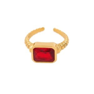 Détail de la bague dorée avec zircon rouge rectangulaire et anneau à texture torsadée