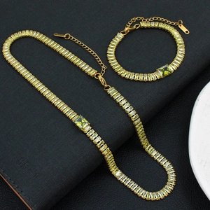 Détails de l'ensemble bijoux dorés avec cristaux verts rectangulaires sur fond noir