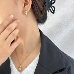 Primer plano de conjunto de joyas de corazón dorado con piedras de circón azul y rosa