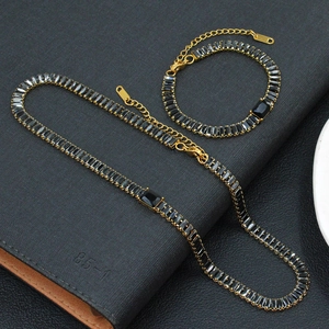 Détail d'un ensemble de bijoux dorés avec pierres rectangulaires noires sur fond texturé
