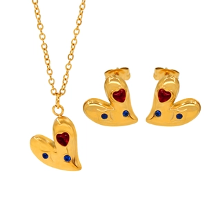 Detalle macro de un juego de joyas de corazón dorado con piedras de circón rojo y azul