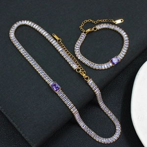 Détail d'un ensemble de bijoux dorés avec zircons rectangulaires violets et clairs