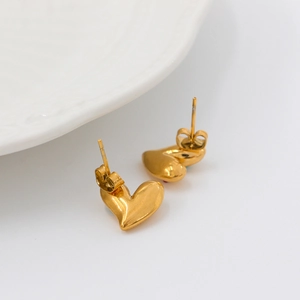 Pendientes de corazón en acero inoxidable dorado sobre un plato de cerámica blanca
