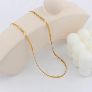 Detailed view of the sleek golden herringbone chain necklace on a minimalist display