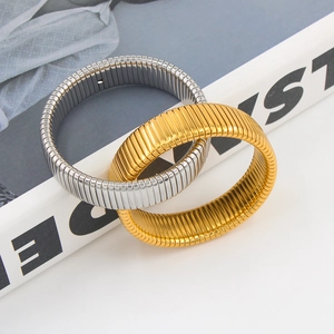 Coppia di bracciali elastici Tubogas in oro e argento su una rivista di tendenza