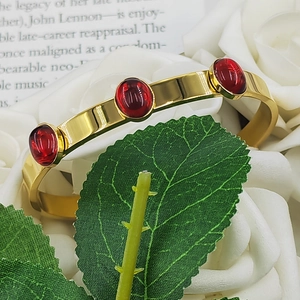 Detail of vintage gold-plated cuff bracelet featuring three inlaid oval red stones