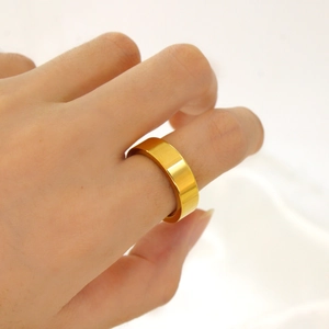 Primo piano dell'anello a fascia larga dorato in acciaio inossidabile indossato al dito