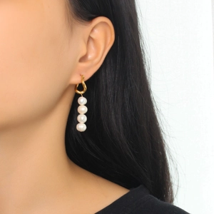 Elegant gold twisted hoop earrings with four dangling white pearls on a model