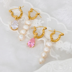 Gold hoop earrings featuring teardrop crystal and tiered pearl drops on white lace background