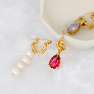 Detail of gold hoop earrings with white pearls and colorful teardrop zircon pendants