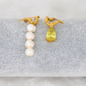 Detail of elegant gold drop earrings with white pearls and yellow teardrop gemstone
