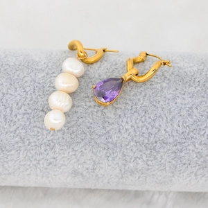 Detailed shot of gold twisted hoop earrings with white pearls and purple drop zircon