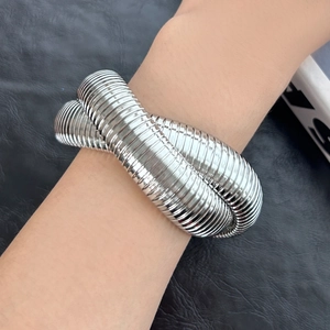 Detailansicht eines breiten, gerippten, flexiblen Metallarmbands am Handgelenk in Silber