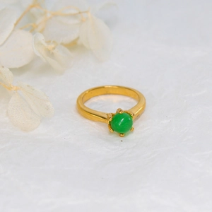 Detailed view of a vintage gold ring featuring a green emerald-style stone in a six-prong setting
