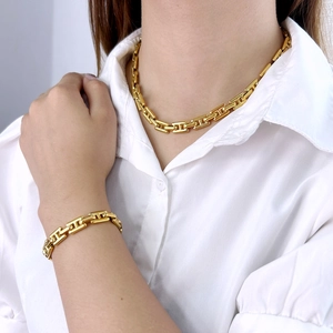 Primer plano de collar y pulsera de eslabones H en acero de titanio dorado en modelo