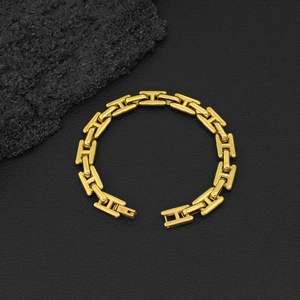 Primer plano de pulsera de acero de titanio con eslabones H dorados sobre cuero negro