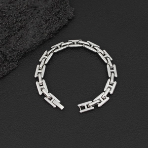 Primer plano de una pulsera de eslabones H en plata pulida sobre un fondo negro