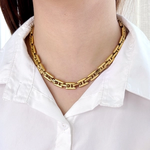 Collar minimalista de acero de titanio dorado con eslabones en H usado por una modelo