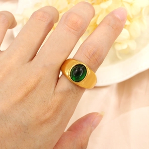 Bague vintage dorée avec pierre émeraude ovale portée dans un cadre élégant