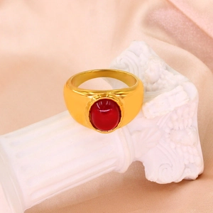 Gros plan d'une bague chevalière plaquée or 18K avec une pierre rouge ovale sur un pilier