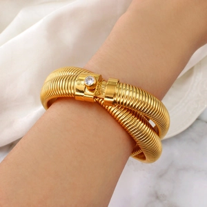 Detailed view of a gold spiral snake bone bracelet with sparkling round diamond accent