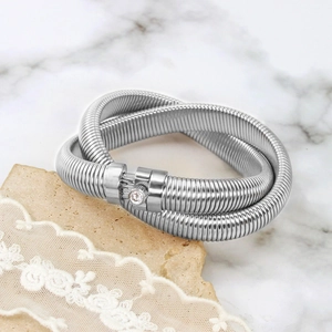 Detail view of silver spiral bracelet with central gemstone on marble and lace background