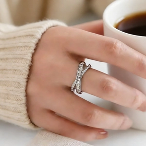 Close-up of elegant silver criss-cross ring with zircon pavé setting on female finger