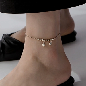 Elegant beaded anklet with lotus leaf pendants in gold finish worn on the ankle