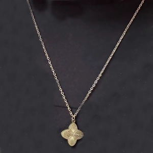 Detailed close-up of a golden laser-cut flower pendant necklace with radial texture