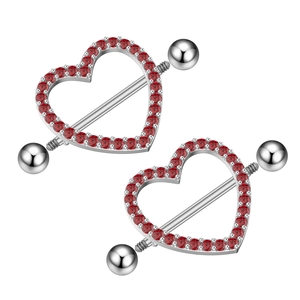 Macro view of heart-shaped stainless steel nipple rings with inlaid red cubic zirconia stones