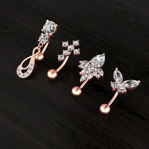 Détail de quatre piercings de nombril en or rose avec zircons sur bois sombre