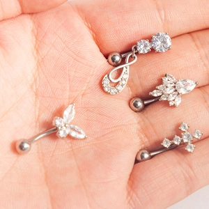 Vue détaillée de piercings de nombril en acier avec papillon et pierres de zircon