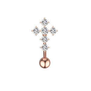 Détail macro d'un piercing de nombril en forme de croix dorée avec zircons clairs