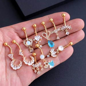 Detailopname van gouden navelpiercings met zirkoon in de hand voor schaalindicatie
