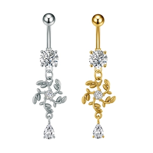 Dettaglio di piercing all'ombelico in oro e argento con fiore e pendente in zircone